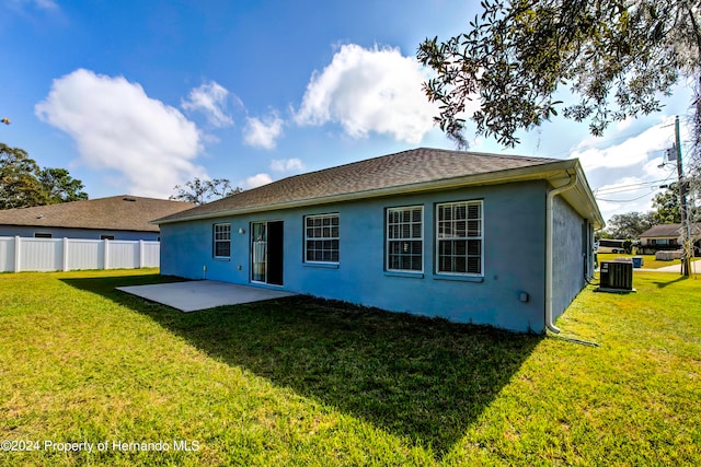 rear view of property with central air condition unit, a lawn, and a patio