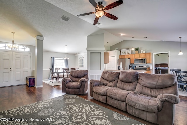 living room with ceiling fan with notable chandelier, dark hardwood / wood-style flooring, and vaulted ceiling