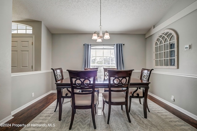 dining space with a textured ceiling, an inviting chandelier, hardwood / wood-style floors, and plenty of natural light