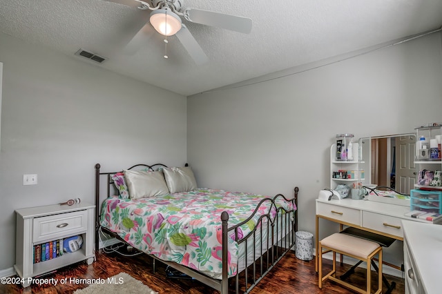 bedroom with a textured ceiling, ceiling fan, and dark hardwood / wood-style floors