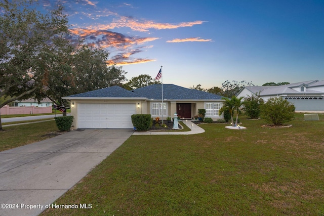 ranch-style home with a garage and a yard