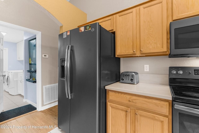 kitchen featuring light brown cabinets, washer / dryer, light hardwood / wood-style floors, and stainless steel appliances