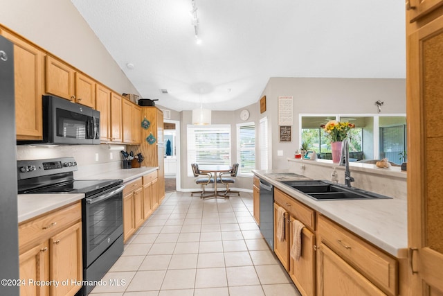 kitchen featuring stainless steel appliances, vaulted ceiling, sink, light tile patterned floors, and decorative light fixtures