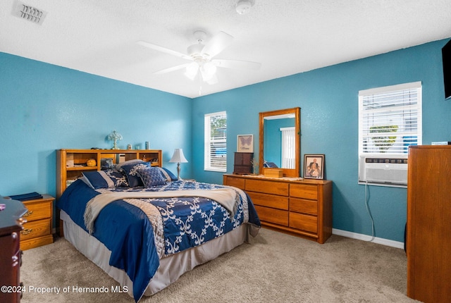 carpeted bedroom with ceiling fan, multiple windows, cooling unit, and a textured ceiling