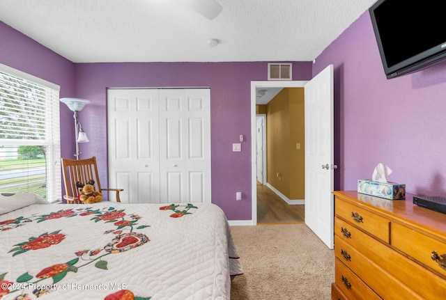 bedroom with a closet, a textured ceiling, and light carpet