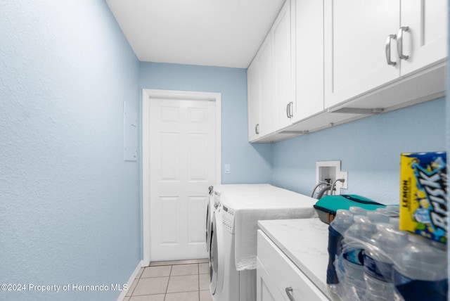 laundry area with cabinets, washing machine and dryer, and light tile patterned floors