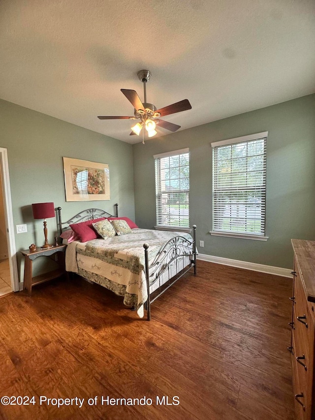 bedroom with a textured ceiling, dark wood-type flooring, and ceiling fan