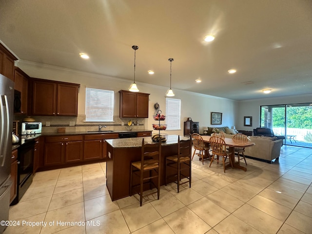 kitchen with light tile patterned flooring, dark stone counters, pendant lighting, sink, and a center island