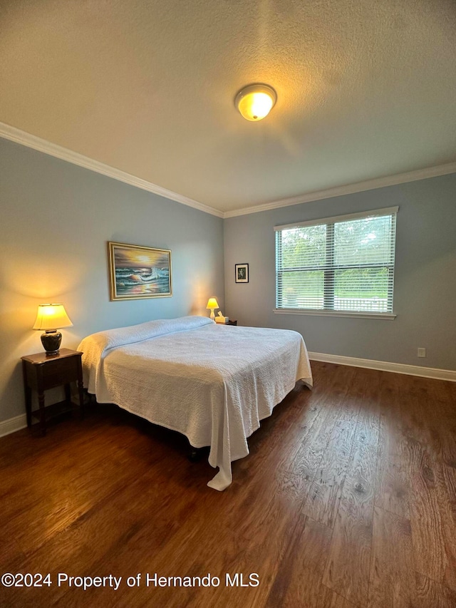 bedroom featuring dark hardwood / wood-style floors, a textured ceiling, and ornamental molding