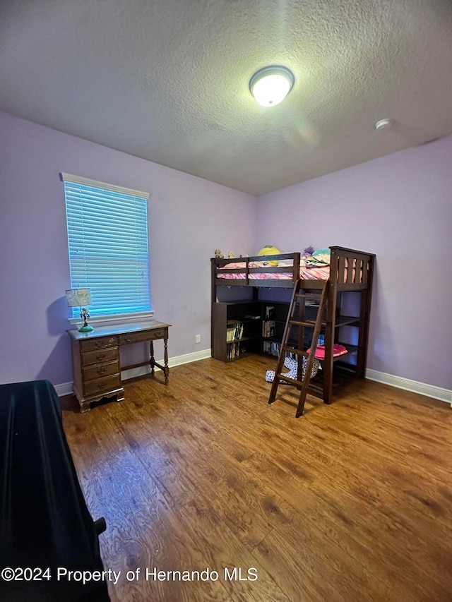 bedroom featuring hardwood / wood-style floors and a textured ceiling