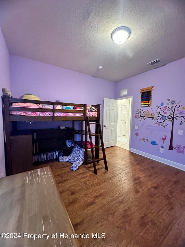 bedroom featuring hardwood / wood-style flooring and a textured ceiling