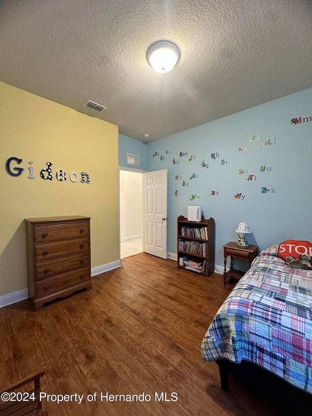 bedroom featuring dark hardwood / wood-style flooring and a textured ceiling