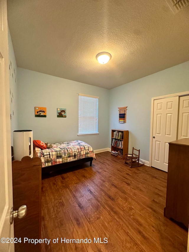 bedroom with a textured ceiling and dark hardwood / wood-style flooring