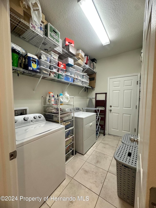 washroom with washing machine and clothes dryer, light tile patterned floors, and a textured ceiling