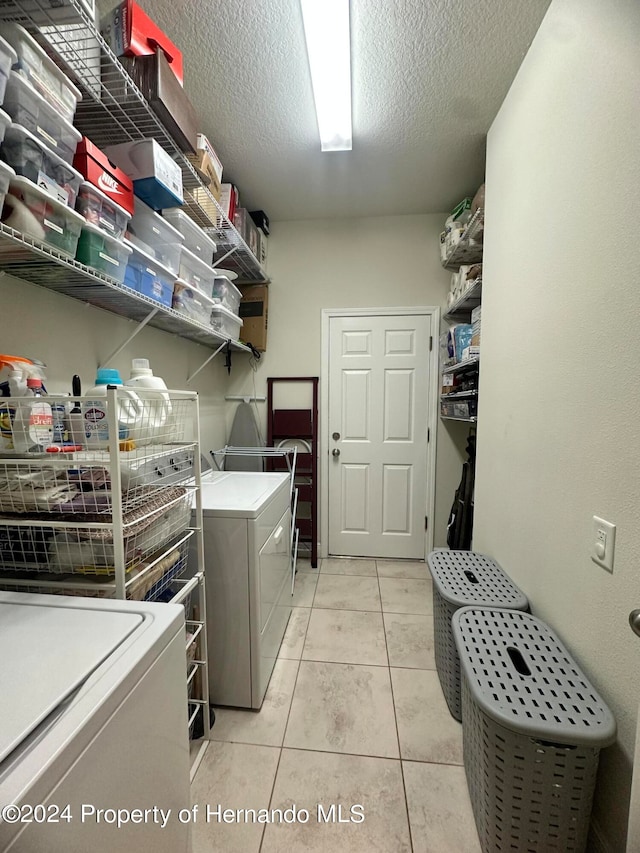 laundry area with separate washer and dryer, a textured ceiling, and light tile patterned floors