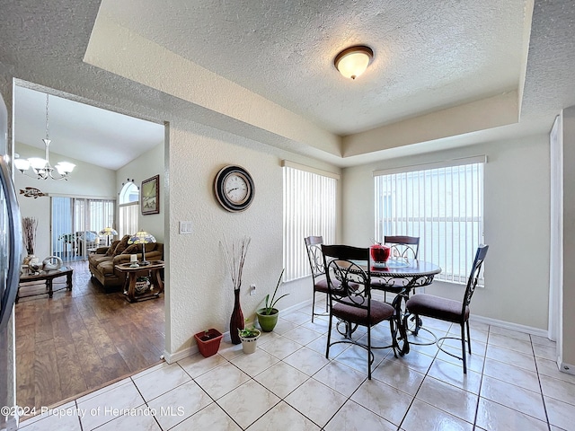 dining space with light hardwood / wood-style flooring, a textured ceiling, a notable chandelier, and plenty of natural light