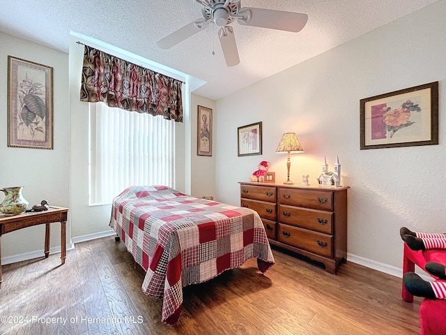 bedroom with a textured ceiling, wood-type flooring, and ceiling fan