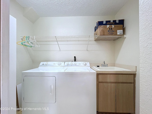 washroom with cabinets, washer and clothes dryer, a textured ceiling, and sink