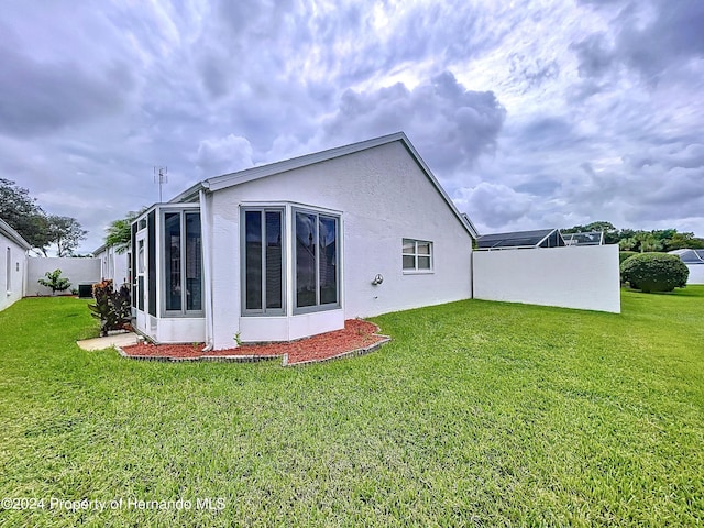 rear view of property featuring a lawn and a sunroom