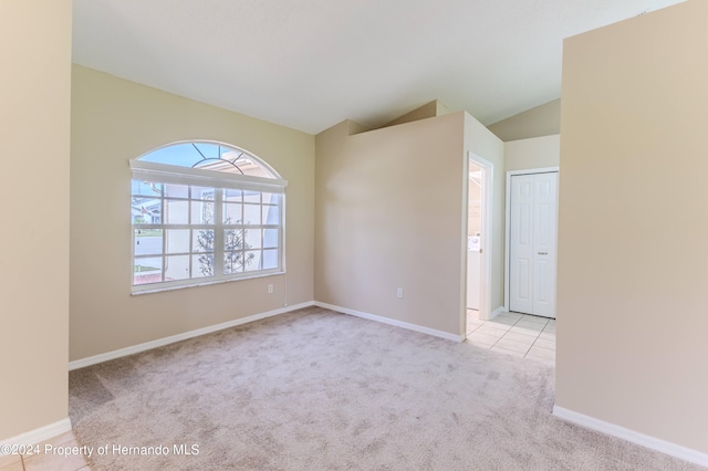 unfurnished room featuring lofted ceiling and light carpet