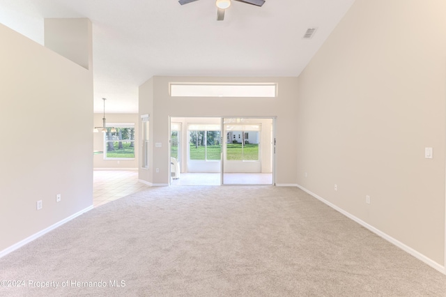 unfurnished living room with high vaulted ceiling, light carpet, and ceiling fan