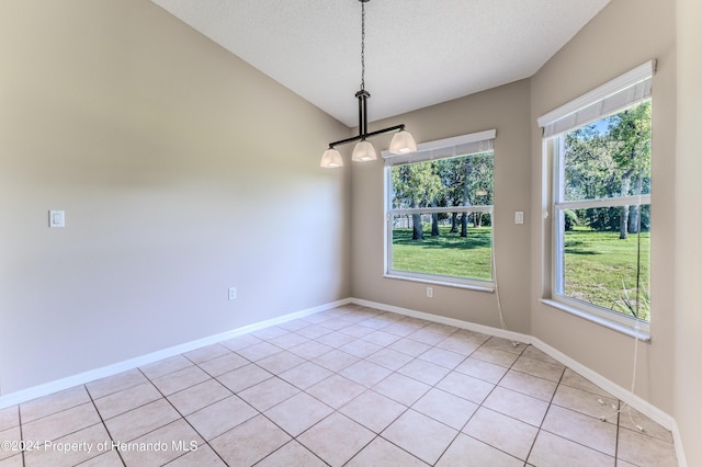 tiled empty room featuring a textured ceiling and vaulted ceiling