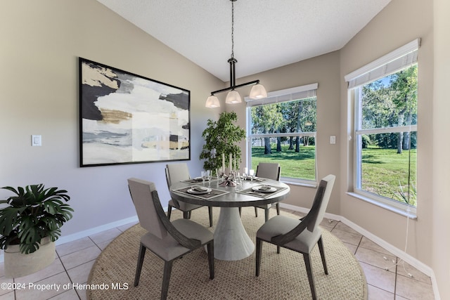 tiled dining area with lofted ceiling and a textured ceiling