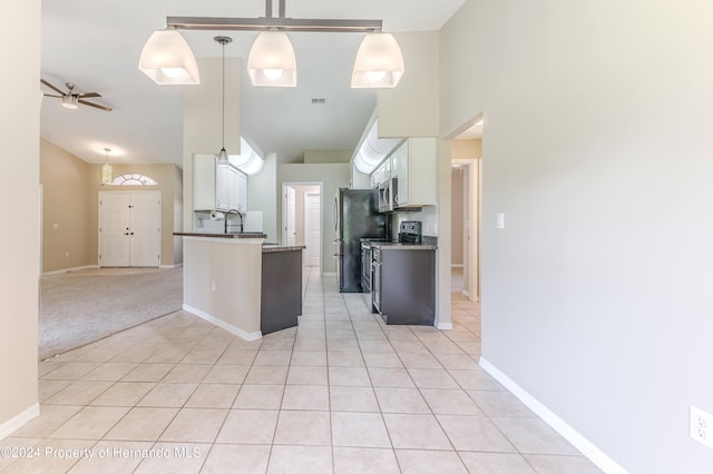 kitchen with hanging light fixtures, stainless steel appliances, light carpet, and white cabinets