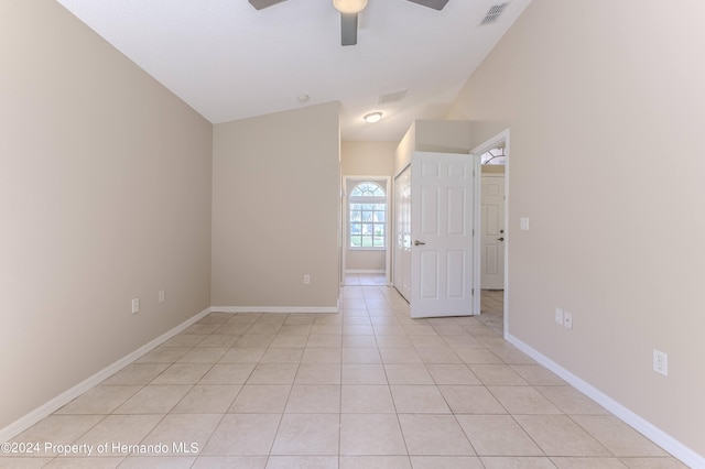 empty room with lofted ceiling, light tile patterned floors, and ceiling fan