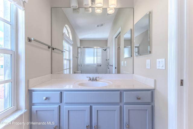 bathroom featuring a shower with shower door, vanity, and plenty of natural light