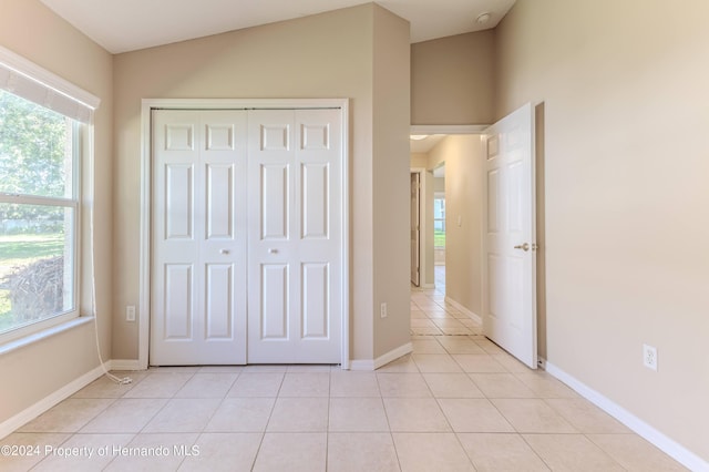 unfurnished bedroom with light tile patterned floors, a closet, and vaulted ceiling