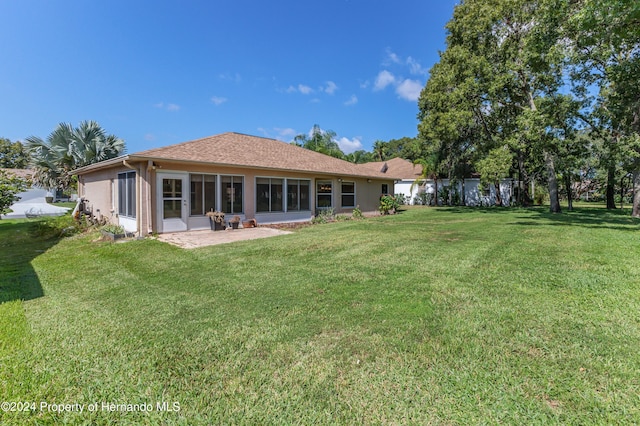 back of property with a lawn and a patio area