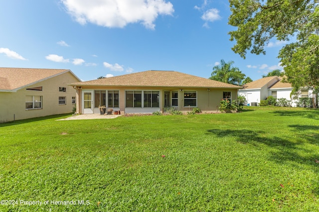 back of property with a lawn and a sunroom