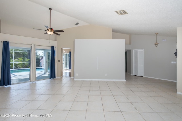 empty room with high vaulted ceiling, light tile patterned floors, and ceiling fan