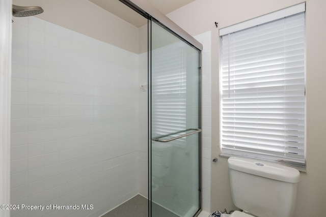 bathroom featuring toilet, an enclosed shower, and a healthy amount of sunlight