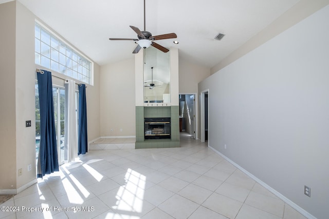 unfurnished living room with high vaulted ceiling, a tiled fireplace, ceiling fan, and light tile patterned floors