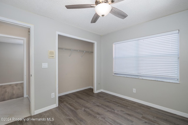 unfurnished bedroom featuring ceiling fan, dark hardwood / wood-style floors, a textured ceiling, and a closet