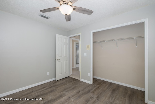 unfurnished bedroom with dark wood-type flooring, ceiling fan, a textured ceiling, and a closet