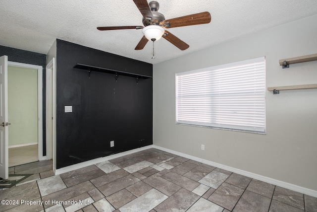 empty room with ceiling fan and a textured ceiling