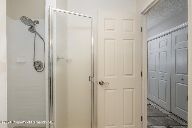 bathroom with a textured ceiling and a shower with shower door