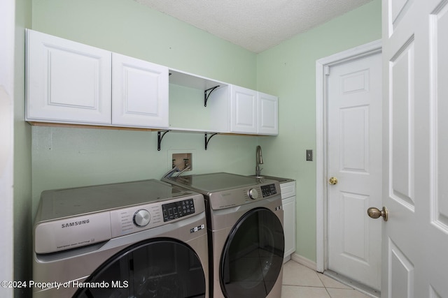 clothes washing area featuring light tile patterned flooring, separate washer and dryer, a textured ceiling, cabinets, and sink