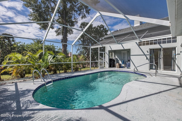 view of pool with glass enclosure and a patio area