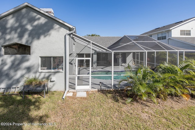 back of property featuring a lanai and a lawn