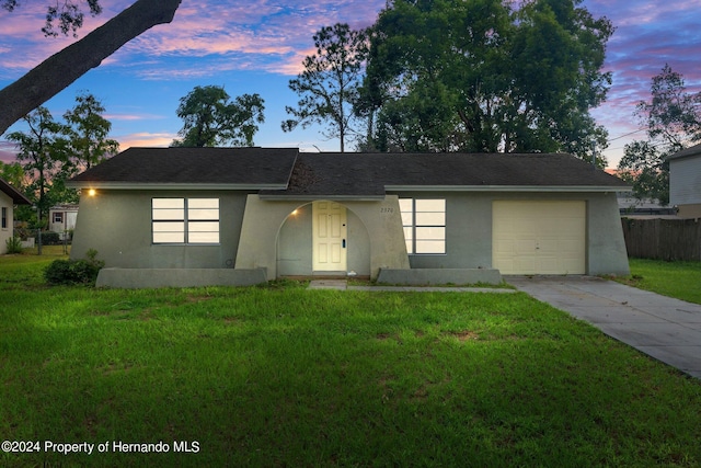 ranch-style house with a garage and a lawn