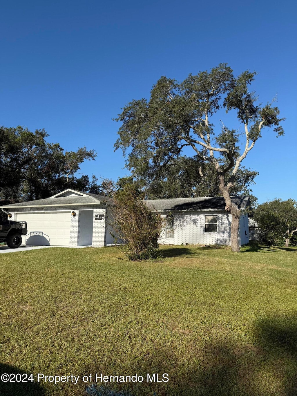 ranch-style home with a garage and a front lawn