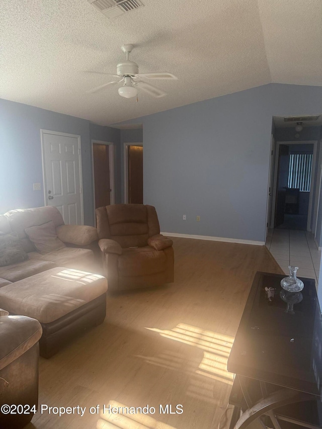 living room featuring lofted ceiling, a textured ceiling, hardwood / wood-style flooring, and ceiling fan