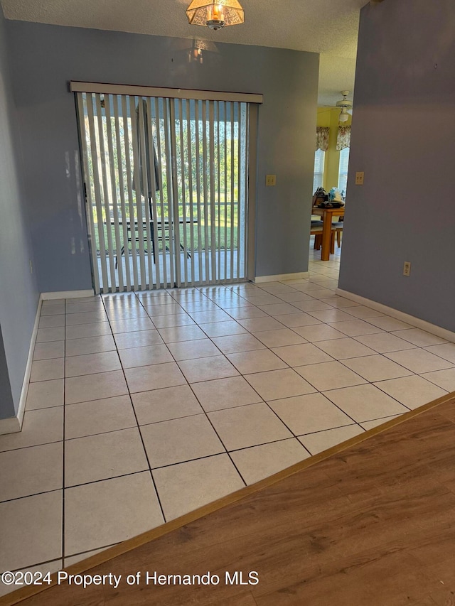 tiled empty room featuring a textured ceiling