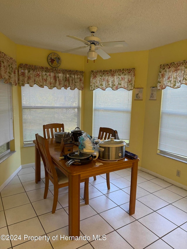 tiled dining area with a textured ceiling and ceiling fan