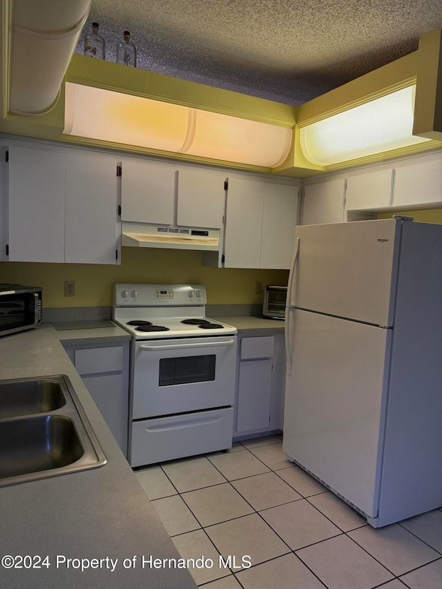 kitchen featuring white appliances, a textured ceiling, sink, and light tile patterned flooring