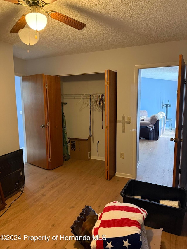 bedroom featuring ceiling fan, a textured ceiling, a closet, and light hardwood / wood-style flooring